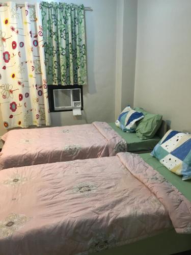 Cette chambre comprend deux lits et une fenêtre avec des rideaux. dans l'établissement AGB Anchorage Inn, studio room - 2 single beds, à Manille