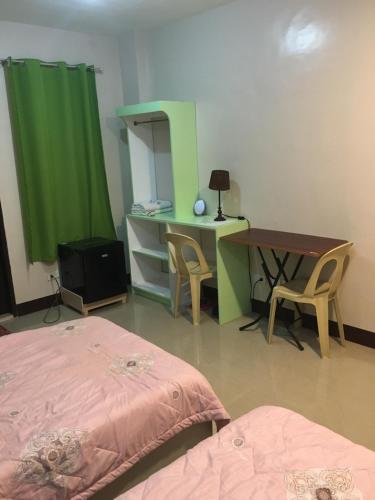 Cette chambre comprend deux lits, un bureau et un rideau vert. dans l'établissement AGB Anchorage Inn, studio room - 2 single beds, à Manille