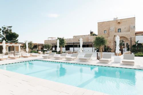 a pool with white lounge chairs and a swimming pool at Masseria Corsano in Nardò
