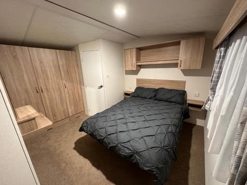 a small bedroom with a bed and wooden cabinets at Billing Aquadrome Luxury Static Caravan in Great Billing