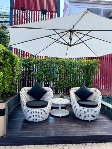 two chairs and a table with an umbrella at Yotaka Bangkok Hotel in Bangkok