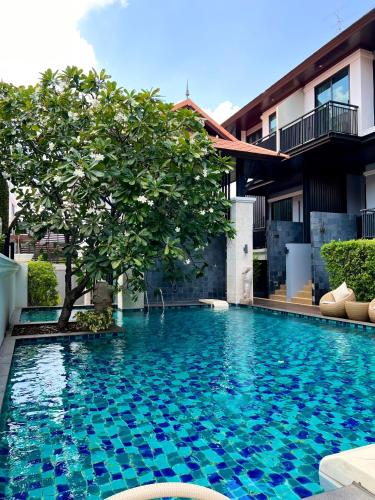 a swimming pool with a tree in front of a building at Yotaka Bangkok Hotel in Bangkok