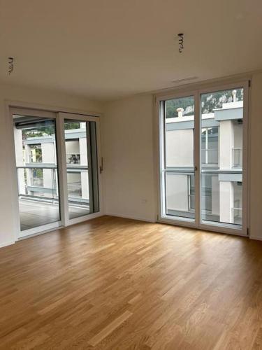 una stanza vuota con ampie finestre e pavimento in legno massello di The R Apartment Vogelberg, Gym, Balkon, Parking a Balsthal