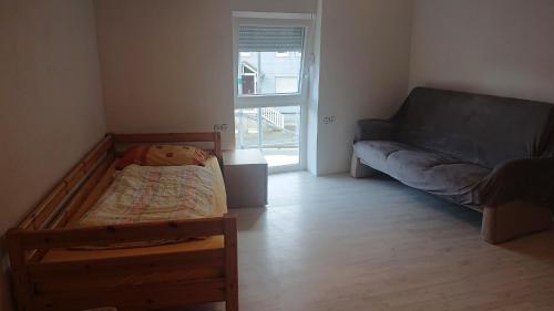 ein kleines Schlafzimmer mit einem Bett und einem Sofa in der Unterkunft Monteur - Ferienwohnung Gönnern für 1 Person in Gönnern