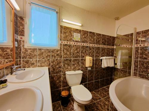 a bathroom with a sink and a toilet and a tub at Will's Hotel in Narbonne