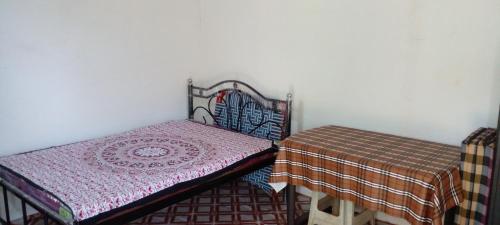 um quarto com uma cama e uma mesa com um cobertor em Mendonca's Home Stay em Pernem