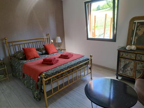 Un dormitorio con una cama con almohadas rojas y una mesa. en Chambre dans chalet avec piscine, en Saint-Jean-en-Royans