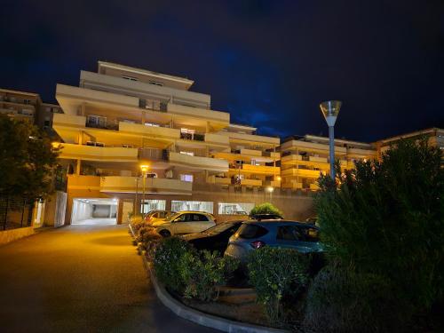 un estacionamiento frente a un edificio por la noche en Appartement cosy climatisé dans résidence fermée, en Sarrola-Carcopino