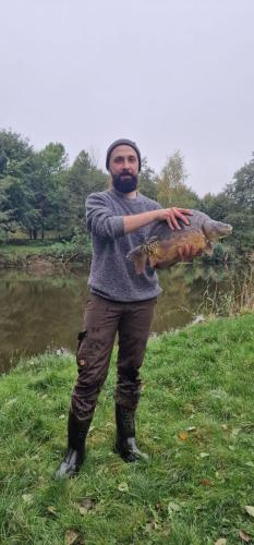 a man holding a fish in front of a river at Ranczo Brusno in Połczyn-Zdrój