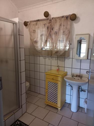 W łazience znajduje się żółta umywalka i prysznic. w obiekcie Tarentilos w mieście Tzaneen
