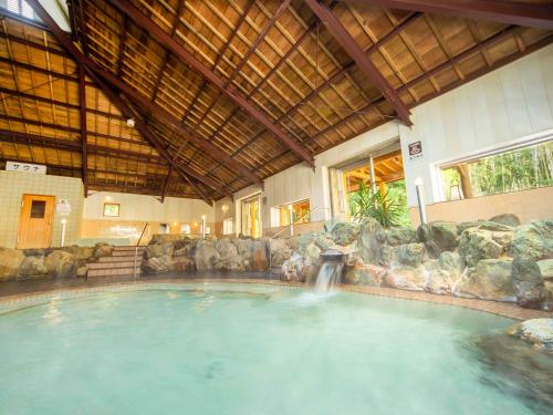 een groot zwembad met een waterval in een gebouw bij Yukai Resort Premium Hotel Ranpu in Hirado