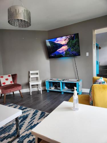 a living room with a tv on the wall at Maison chaleureuse, énergétique et florale in Sherbrooke