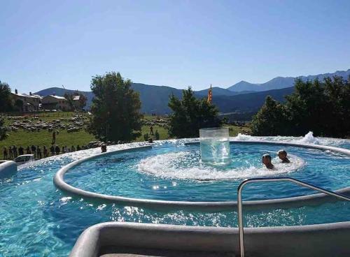 a pool with a water fountain with two people in it at Chalet cosy-vue sur la montagne & montgolfières in Saillagouse