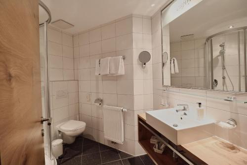 a bathroom with a sink and a toilet and a mirror at Hotel Garni & Aparthotel COLLINA in Ischgl