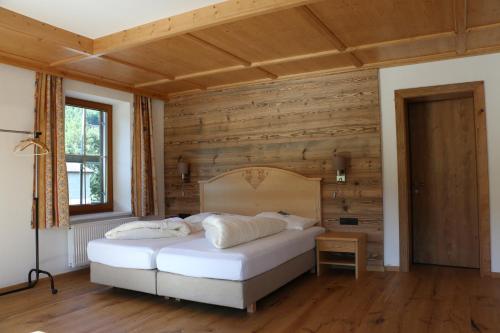 a bedroom with a white bed and wooden walls at Gasthaus Marie in Achenkirch