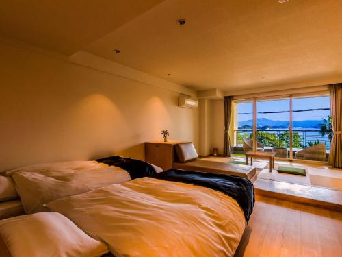 1 dormitorio con 2 camas y ventana grande en Yukai Resort Premium Shirahama Gyoen, en Shirahama