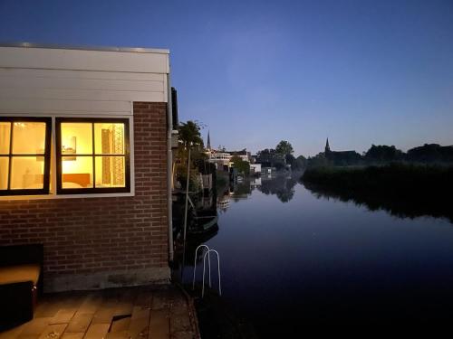um edifício ao lado de um rio com uma janela em Zelfstandig appartement - 10 minuten tot Amsterdam em Ilpendam