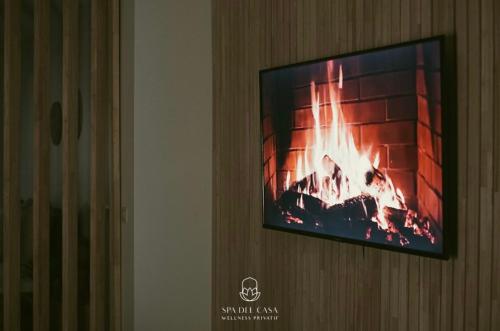 a flat screen tv hanging on a wall with a fireplace at Spa Niagara privé avec jacuzzi in Herstal