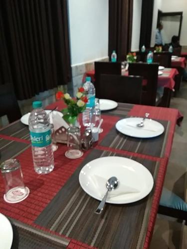 uma mesa com pratos brancos e garrafas de água em HOTEL OM SHIVAAY INN em Rishikesh
