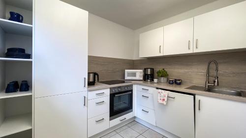 a kitchen with white cabinets and a sink at Fewo Graal in Graal-Müritz