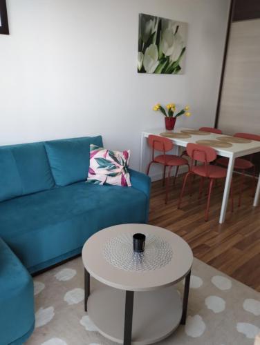 a living room with a blue couch and a table at Apartament Gardena Olsztyn in Olsztyn