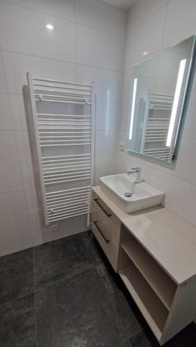 a white bathroom with a sink and a mirror at Luxusní apartmány Čerťák in Vaclavov u Bruntalu