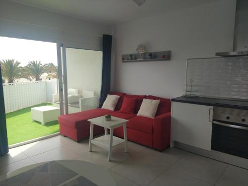 a living room with a red couch and a table at Apartment El Sueño - GREAT SEA VIEWS - SWIMMING POOL - free Wifi- smart TV-Residence SENATOR el majo in Costa Teguise