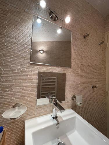 a bathroom with a white sink and a mirror at Le repère de Bianca, le premier de cordée in Montgenèvre