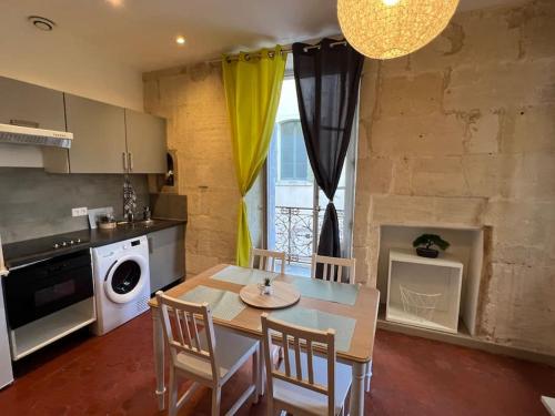 une cuisine avec une table et des chaises dans une cuisine dans l'établissement Appartement en cœur de ville Place du Forum, à Arles
