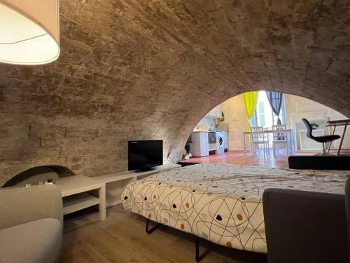 une chambre avec un grand lit dans un mur de briques dans l'établissement Appartement en cœur de ville Place du Forum, à Arles