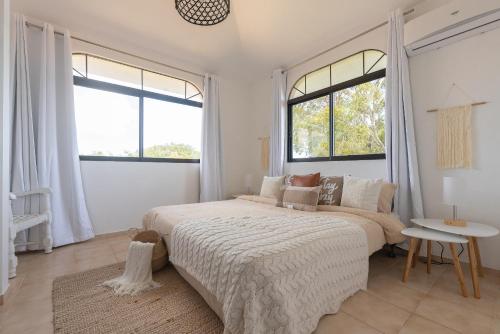 a white bedroom with a large bed and two windows at Flat Anchor Marine Monte Vista in Sosúa
