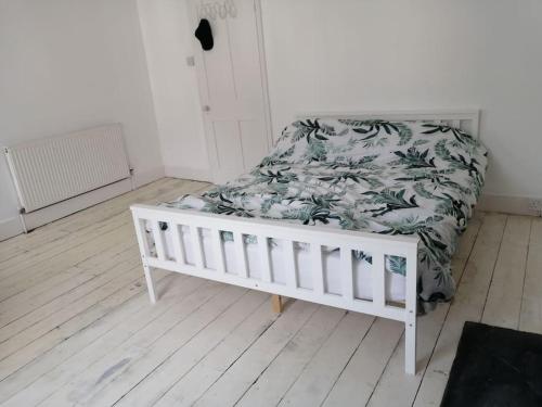 a white crib in a room with a bed at Seaside 2 bed terraced house with garden and free parking in Hastings