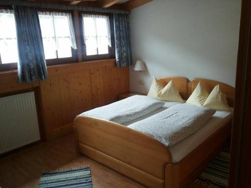 ein Schlafzimmer mit einem großen Bett in einem Zimmer mit Fenstern in der Unterkunft Hirschenhof in Toblach