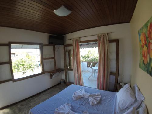 a bedroom with a bed and a window and a table at Pousada Casa das Rosas in Búzios