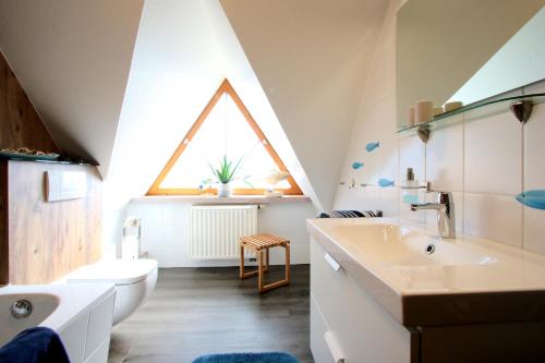シュタインフーデにあるFerienhaus Juleの窓付きのバスルーム、洗面台、トイレが備わります。