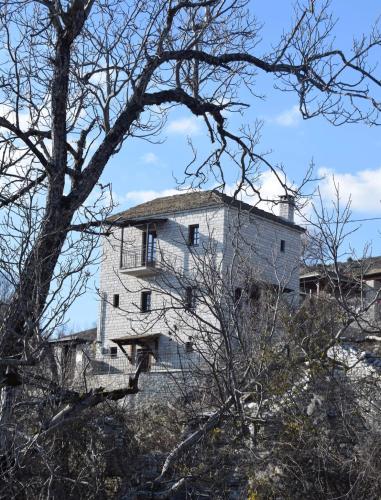 a white building on top of a hill with a tree at Vradeto Guesthouse in Vradéton