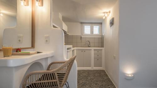 a white kitchen with a sink and a chair at Agia Kyriaki Studios in Agia Kiriaki Beach