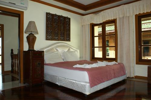 a bedroom with a large bed with red and white sheets at Prince Edouard Apartments & Resort Patong Beach Phuket in Patong Beach