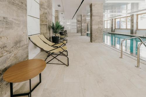 a hallway with chairs and a swimming pool at Hotel Green Park Service Perfected in Garmen