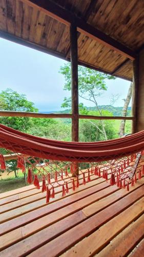 a hammock in a room with a view at Pousada Aconchego do Caboclo in Sapucaí-Mirim