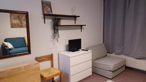 ein Wohnzimmer mit einem Stuhl und einem TV auf einer Kommode in der Unterkunft Studio PRAPOUTEL in Prapoutel