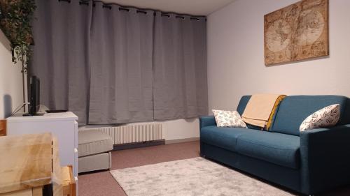 ein Wohnzimmer mit einem blauen Sofa und einem Fenster in der Unterkunft Studio PRAPOUTEL in Prapoutel