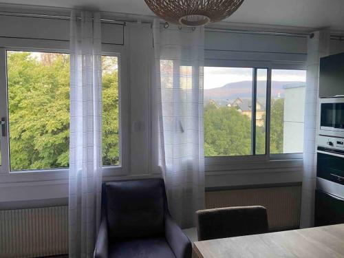 - une cuisine avec 2 grandes fenêtres et une chaise bleue dans l'établissement Studio de 28 m2 lumineux et élégant, à Chambéry