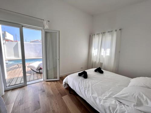 a white bedroom with a bed and a large window at Superbe villa avec piscine à 10 min du centre in La Rochelle