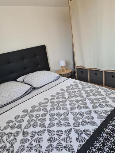 una camera da letto con un letto con copriletto bianco e nero di Gîte de la Gourgeonne a Nervezain