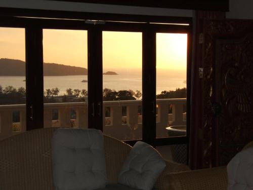 uma sala de estar com vista para o oceano através das janelas em Prince Edouard Apartments & Resort SHA extra plus em Patong Beach