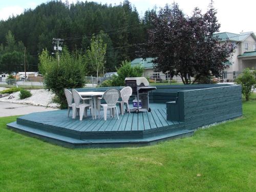 a deck with a grill with chairs and a table at Ponderosa Motor Inn in Golden