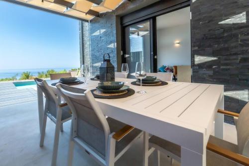 a dining room with a white table and chairs at Villa Vista Mare Lourdata Kefalonia in Lourdhata