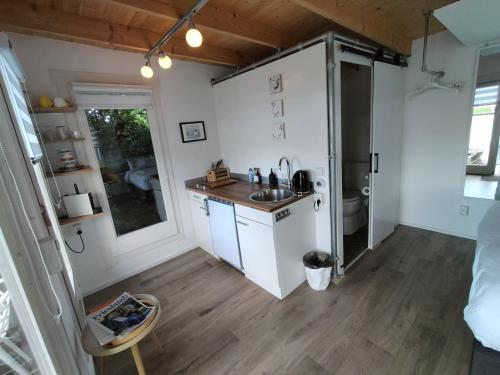 een kleine keuken met een wastafel en een koelkast bij Havenkantoortje in Woudsend