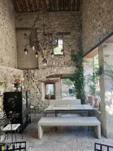 une pièce en pierre avec une table et un lustre dans l'établissement Gite dans Mas de campagne près d'Uzès, à Bouquet